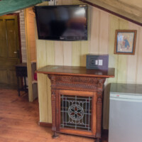Mueble de madera tradicional con televisión en suite abuhardillada con encanto