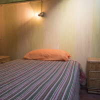 Luz de ambiente acogedora sobre cama en dormitorio rústico de madera