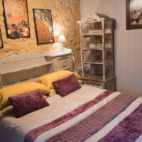 Habitación rústica con paredes de piedra y estantería clásica de forja blanca