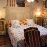 Cama de matrimonio rústica con gran cabecero de madera en la Suite Dante del Hotel Rural Luna del Valle