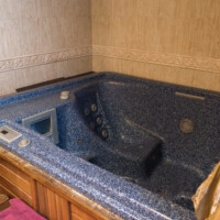 Bañera hidromasaje y jacuzzi privado revestido de madera en suite romántica
