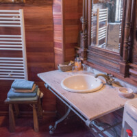 Lavabo rústico sobre estructura de forja y madera en baño de hotel rural pet friendly