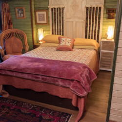 Cama matrimonial rústica con colcha fucsia en la Suite Dragones del Hotel Rural Luna del Valle