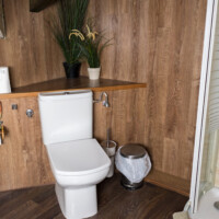 Inodoro y detalles de baño con paredes revestidas de madera noble en hotel rural