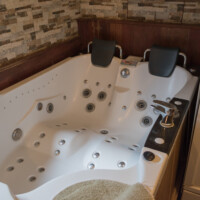 Gran jacuzzi esquinero con hidromasaje y reposacabezas en suite romántica